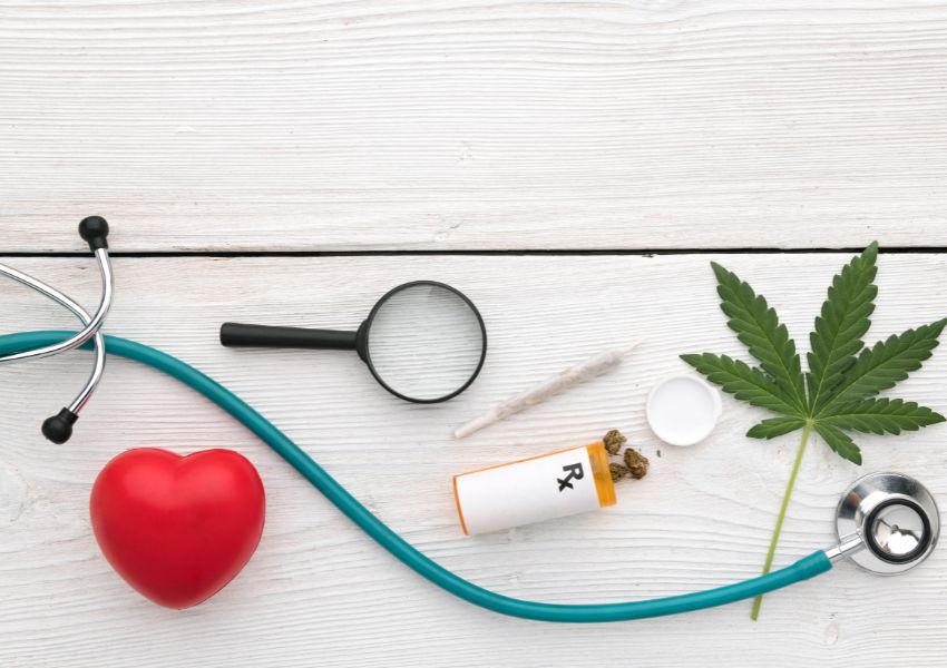 a stethoscope, heart, pill bottle and marijuana leaf on a table